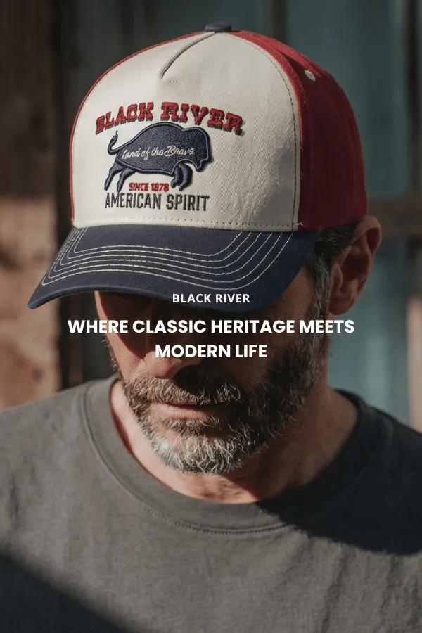 Man sitter på en trälåda i studio och bär en klassisk brun cowboyhatt i filt med bred brätte, mörk denimskjorta och jeans.